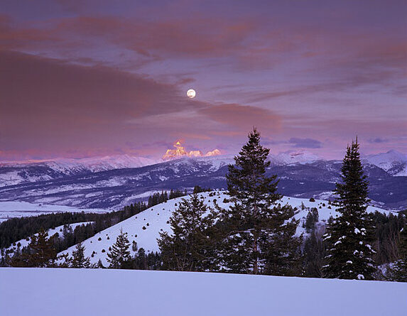A snowy mountain range under a full moon