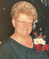 A smiling woman with flowers on her dress below her shoulder