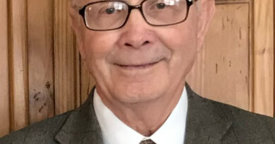 A cropped image of an elderly man wearing glasses smiling