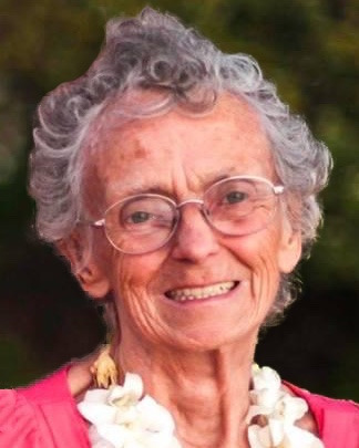 A smiling elderly woman wearing flowers around her neck