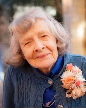 An elderly woman with a flower on her apparel